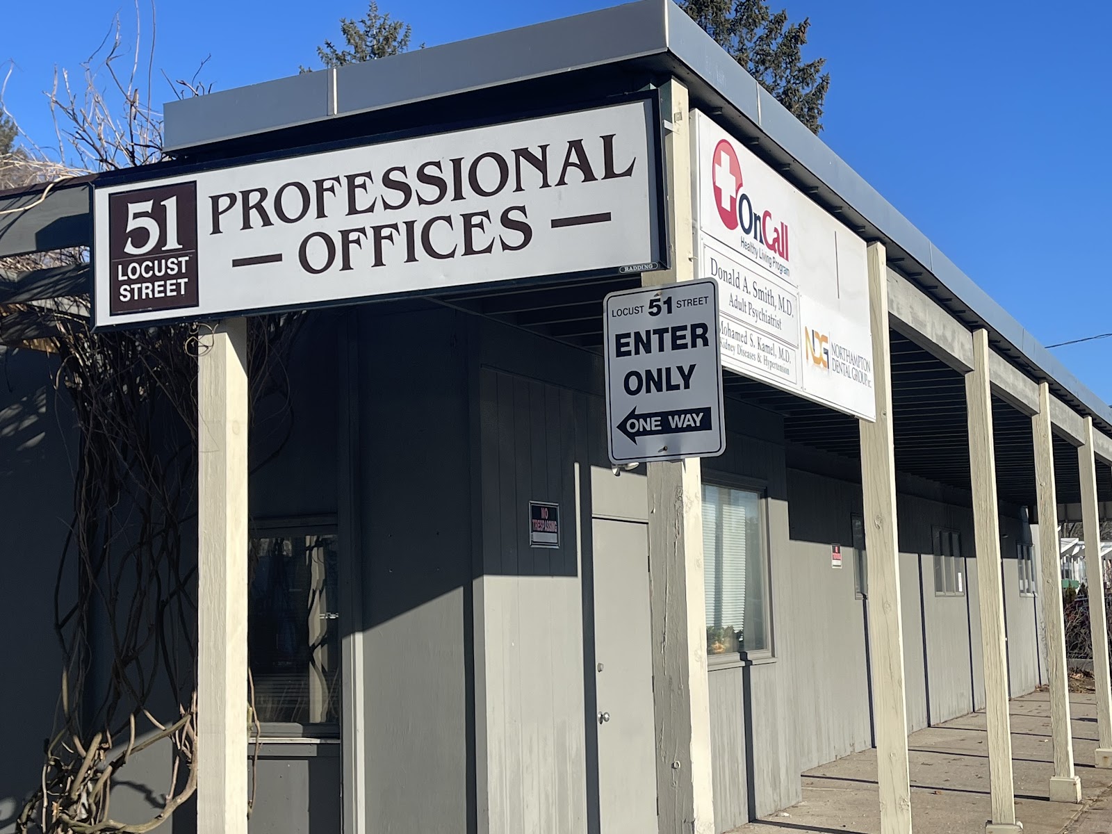 Exterior view of professional offices building entrance at 51 Locust Street with OnCall signage and parking area