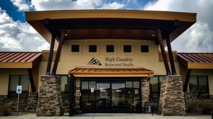 Exterior front view of behavioral health facility with entrance, parking area, and clear sky