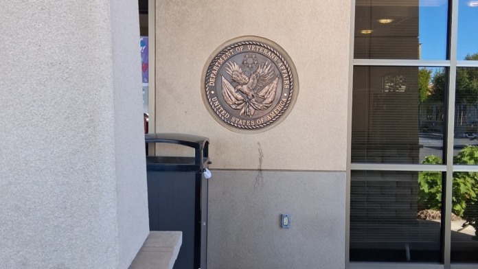 Exterior front entrance showing Department of Veterans Affairs official seal mounted on building facade and glass entry doors