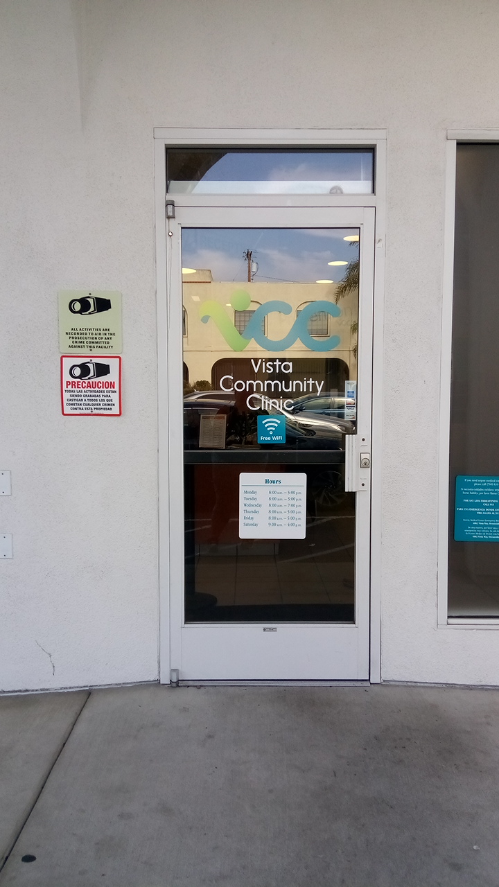 Exterior entrance doors with metal railing, facility signage, and operational information displayed on glass