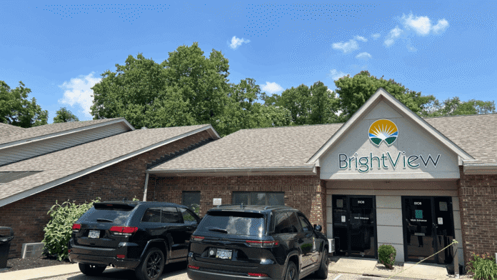 Exterior of brick treatment facility with BrightView signage, gabled roof, windows, landscaping, and parked vehicles.