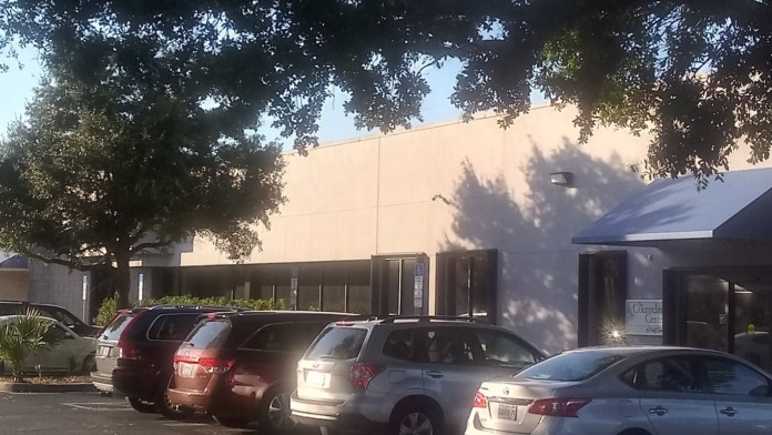 Exterior view showing facility entrance with glass doors, wheelchair accessible parking, and front driveway