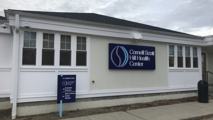 Exterior front showing white facility building with address 121 Wakelee Avenue and directional signs for entrances