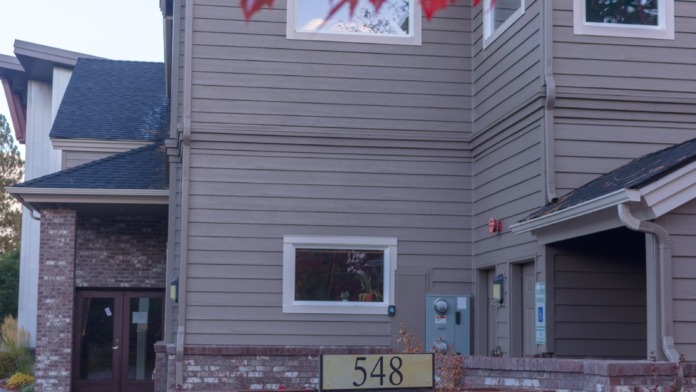 Exterior front facade of treatment facility building with red maple leaves overhead, signage, and landscaped grounds.