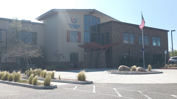 Exterior showing facility signage, cream siding, stone accents, ornamental grasses, and parking