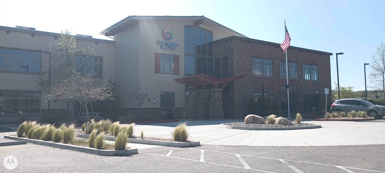 Exterior showing facility signage, cream siding, stone accents, ornamental grasses, and parking