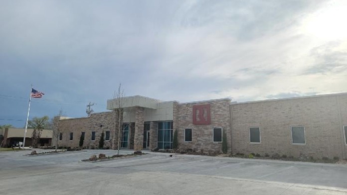 Exterior view of treatment facility showing full front facade with parking lot, American flag, brick and stone construction, and red roof