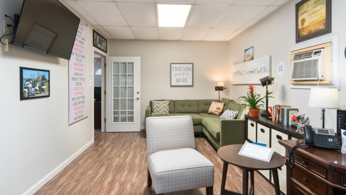 Interior room featuring green sofa, television, framed artwork, and comfortable seating arrangement