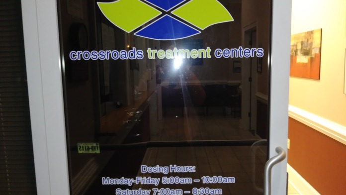 Interior entrance door with Crossroads Treatment Centers logo and posted dosing hours signage