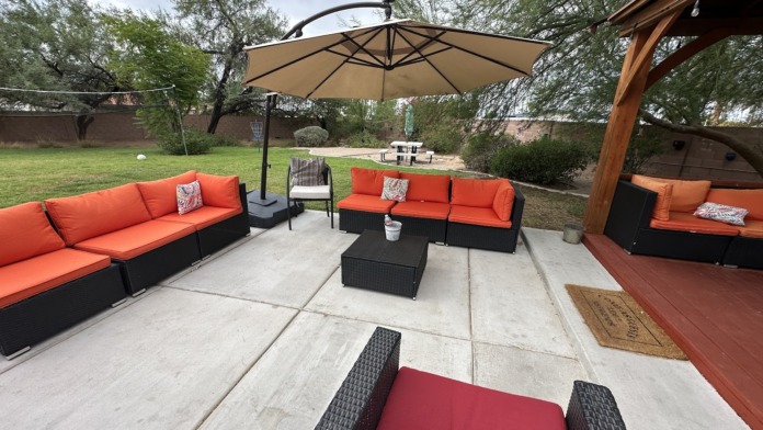 Outdoor recreational area with umbrellas, lounge seating, and landscaped grounds surrounding facility building