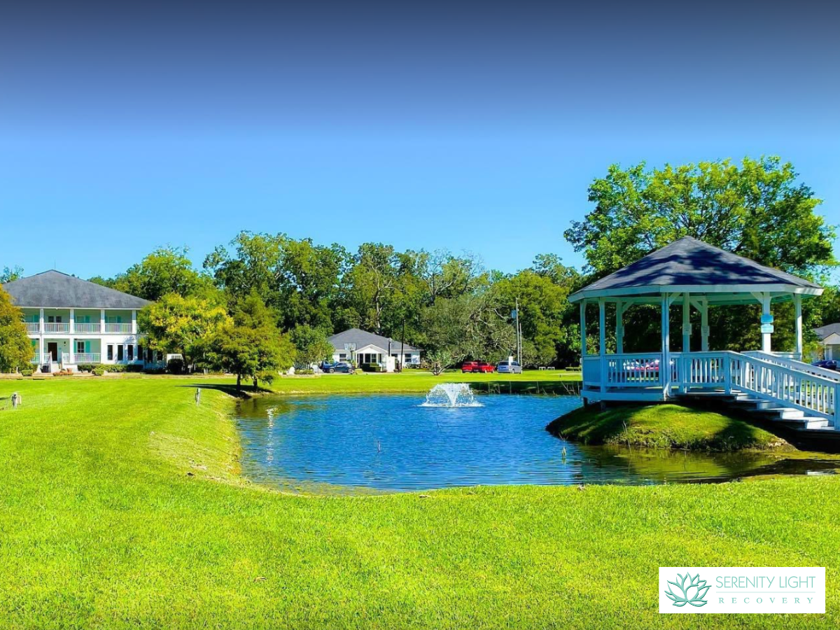 Exterior grounds featuring blue gazebo, pond with fountain, mature trees, green lawn, and facility building in background