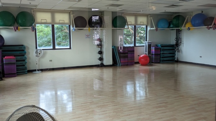 Interior studio with wooden flooring, exercise balls, colorful storage racks, and wall-mounted equipment for group classes