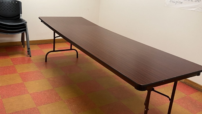 Interior classroom or meeting room with table, chairs, inspirational wall signage about protective factors, and artwork
