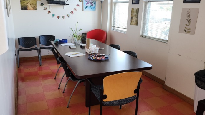 Interior meeting space with large table, colorful chairs, television, and motivational wall art