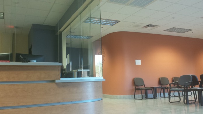 Interior seating area with orange accent wall, multiple chairs, and wall-mounted display screen