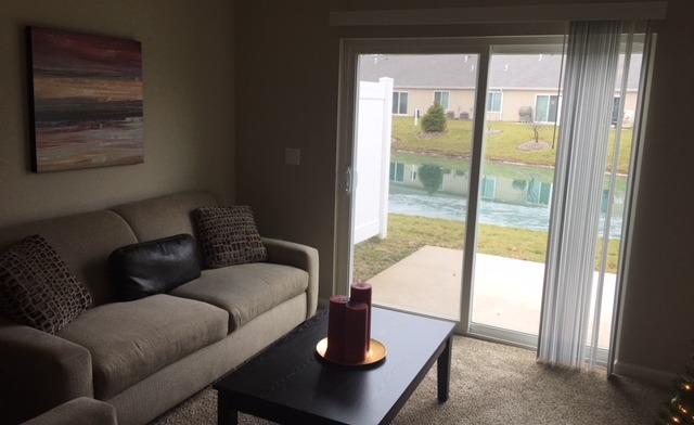 Interior therapy room with circle of blue padded chairs, windows, and television display with facility branding