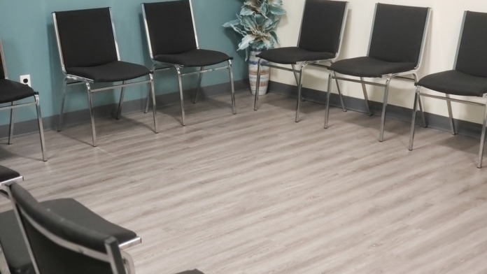 Interior therapy space with multiple black chairs arranged in circle on light wood flooring with accent walls