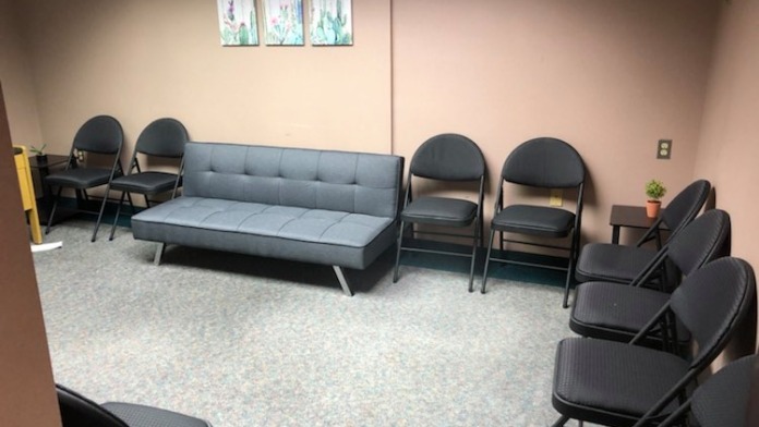 Interior therapy room with multiple chairs, sofa, whiteboard, and decorative artwork on walls