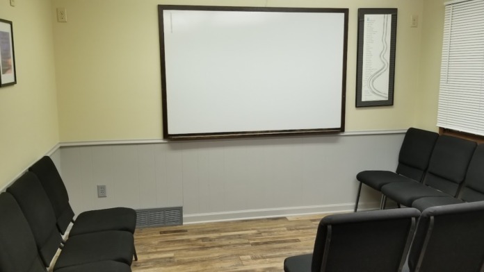 Interior group therapy room with seating arrangement and large presentation whiteboard