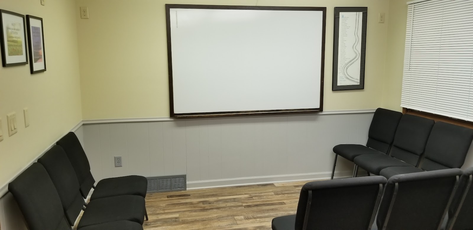 Interior group therapy room with seating arrangement and large presentation whiteboard