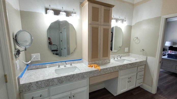 Interior bathroom featuring double vanity with marble countertop, dual mirrors with lighting, and cabinetry storage