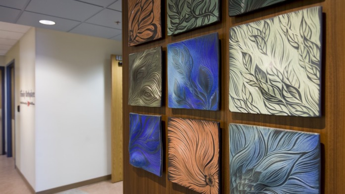 Interior hallway corridor featuring decorative wooden wall panels with colorful abstract artwork, modern facility design and natural lighting