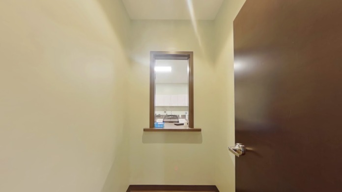 Interior hallway with multiple doors on both sides, stair railings, directional signage, and professional finishes