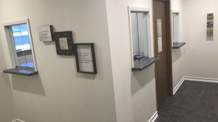 Interior hallway showing multiple wall-mounted windows and treatment room doors with modern architectural design