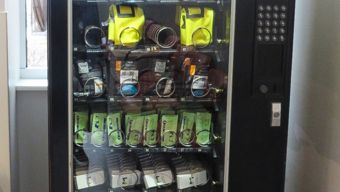 Interior vending machine stocked with harm reduction supplies including pink and yellow safety equipment packages
