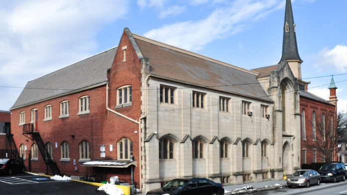 Exterior view of historic brick and stone buildings with parking area, multiple windows, and architectural details