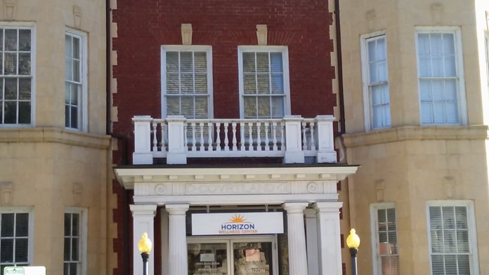 Exterior of multi-story historic facility with cream and maroon facade, multiple windows, and Horizon signage above entrance