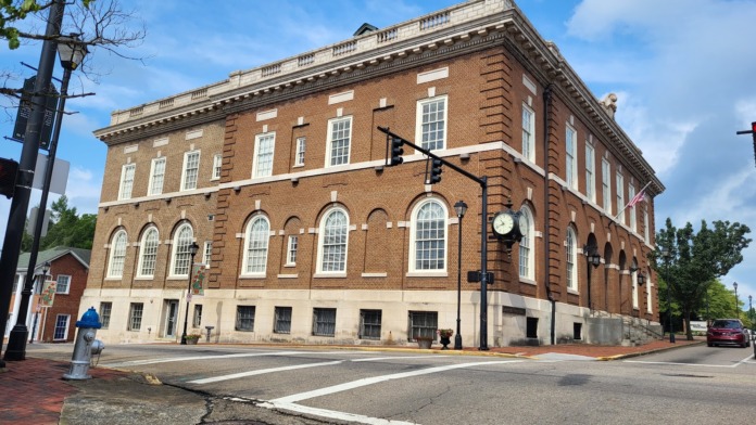 Exterior of brick historic building with white-trimmed windows, ornate cornice, street-level entrance, and surrounding downtown streetscape