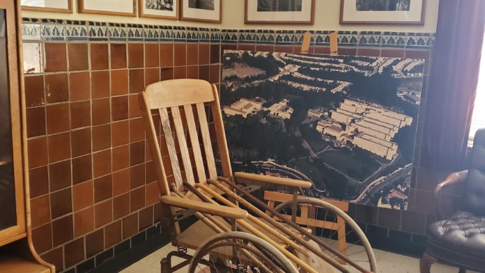 Interior room with vintage framed photographs on walls, wooden furnishings, decorative tilework, and historical memorabilia of facility