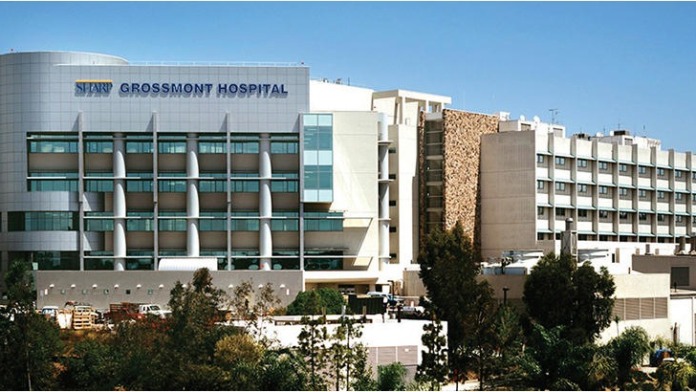 Exterior view showing multiple connected hospital building sections with modern architecture and surrounding landscape