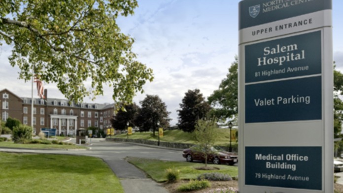 Exterior grounds view of brick hospital building with manicured landscaping and parking area