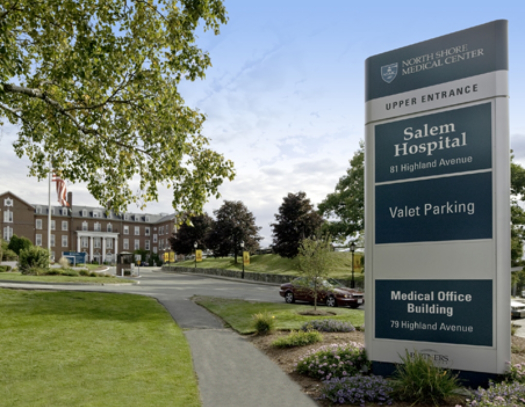 Exterior grounds view of brick hospital building with manicured landscaping and parking area