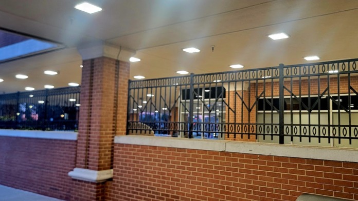 Interior hallway with brick walls, metal railings, recessed lighting, brick columns, and polished flooring