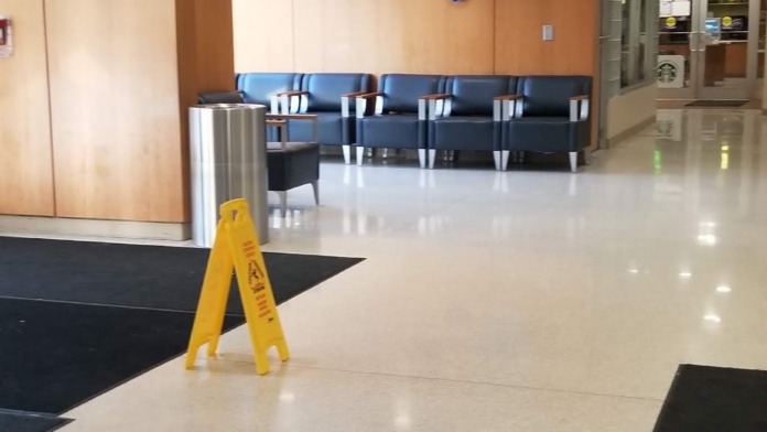 Interior hallway with blue seating chairs, decorative wall art, exit signage, and modern flooring