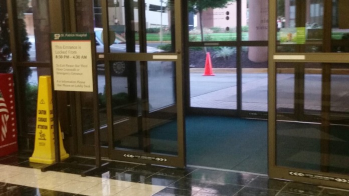 Interior entrance area with glass doors, exit sign, and tiled flooring leading to outdoor entrance