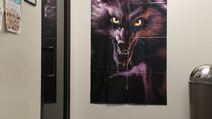 Interior hallway showing motivational wolf artwork on wall with informational posters and trash receptacle