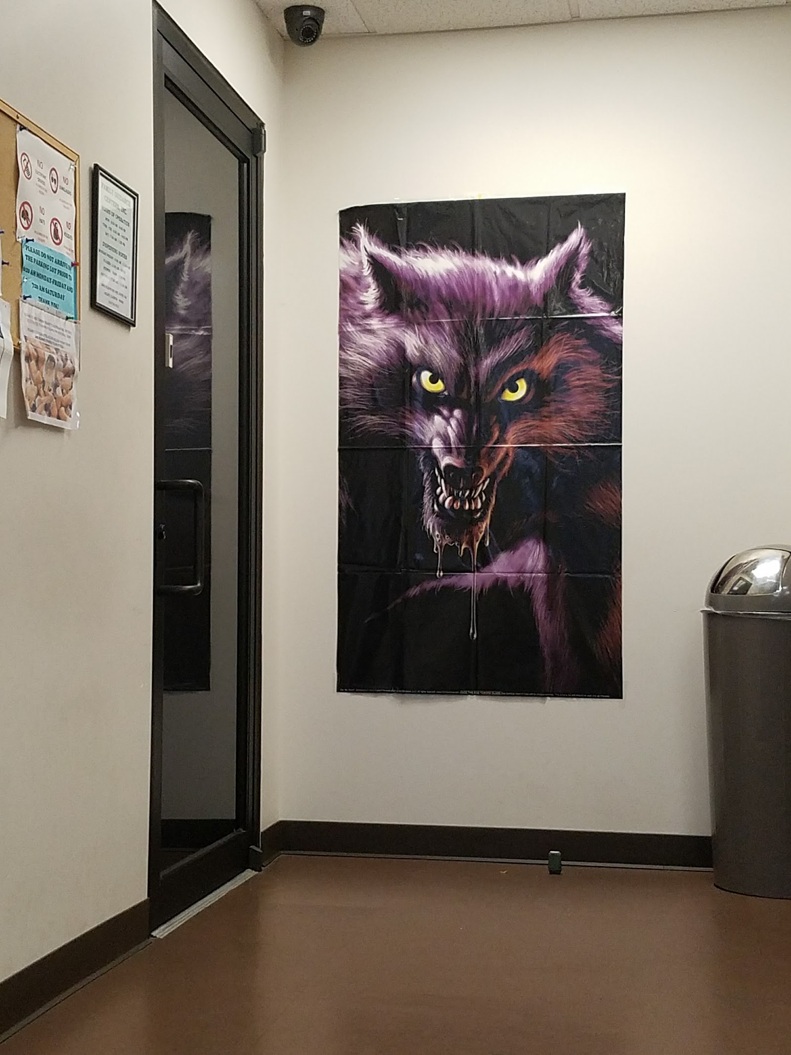 Interior hallway showing motivational wolf artwork on wall with informational posters and trash receptacle