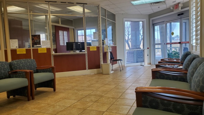 Interior view of clinic lobby showing multiple seating areas, reception counter with glass windows, and tiled flooring