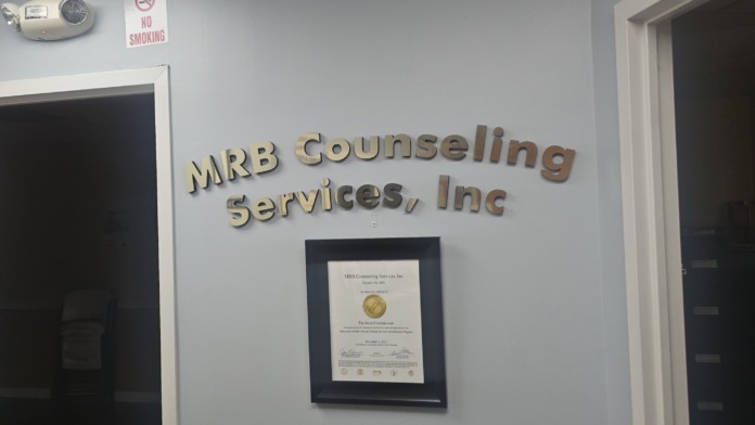 Interior view of MRB Counseling Services reception area showing facility name on wall, framed certification, and no smoking sign