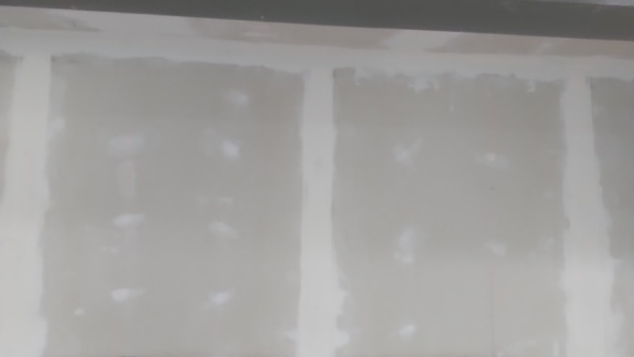 Interior treatment area under renovation showing drywall, multiple windows with construction protection, and electrical boxes