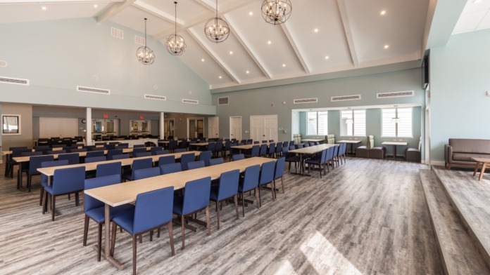Interior conference room with long banquet tables, blue chairs, high vaulted ceiling with skylights for natural light