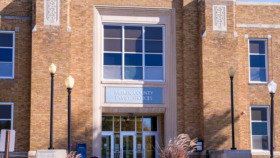 Exterior view of brick building with Litchfield signage, central entrance doors, decorative columns, and landscaped front area