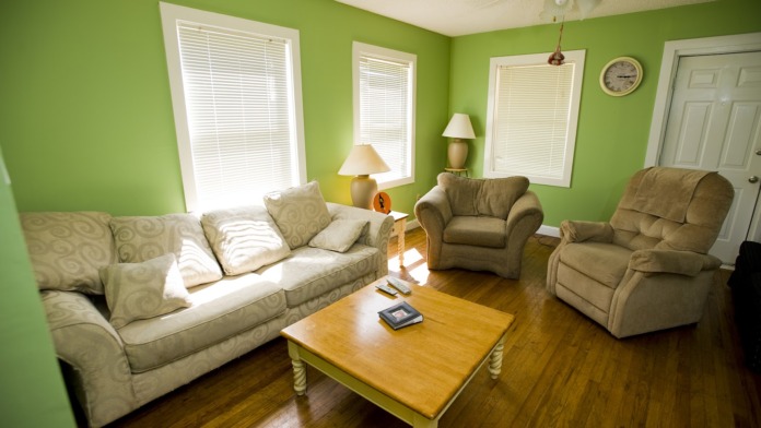 Interior living room with bright green walls, comfortable seating furniture, wooden coffee table, and large windows