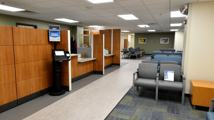 Interior lobby with wooden wall panels, kiosk, seating chairs, and doors to facility areas