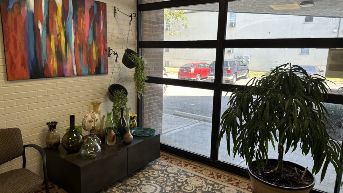 Interior lobby space with black chairs, colorful abstract wall art, decorative plants, and large windows