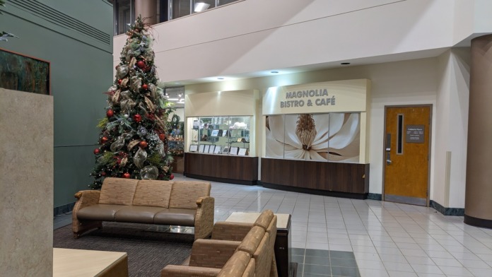 Interior lobby featuring decorated Christmas tree, brown leather seating, and café signage visible in background.